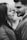 A couple facing each other closely, suggesting intimacy and affection. The woman has long hair and is wearing a textured garment, while the man has a neatly trimmed beard and is dressed in a suit. The image is in black and white, emphasizing contrast and depth.