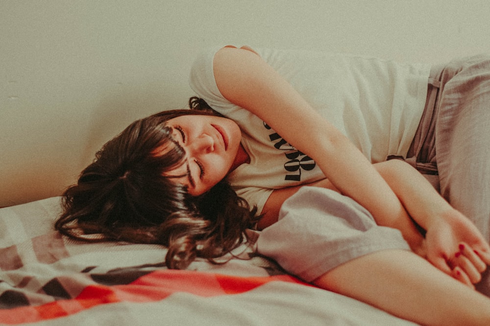 a woman laying on top of a bed next to a window