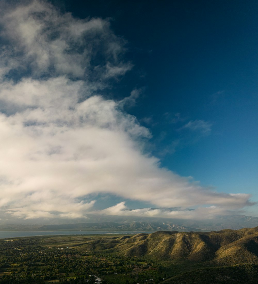 a scenic view of a valley and mountains under a cloudy sky