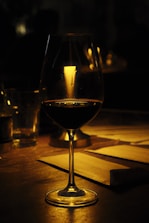 a glass of wine sitting on top of a wooden table