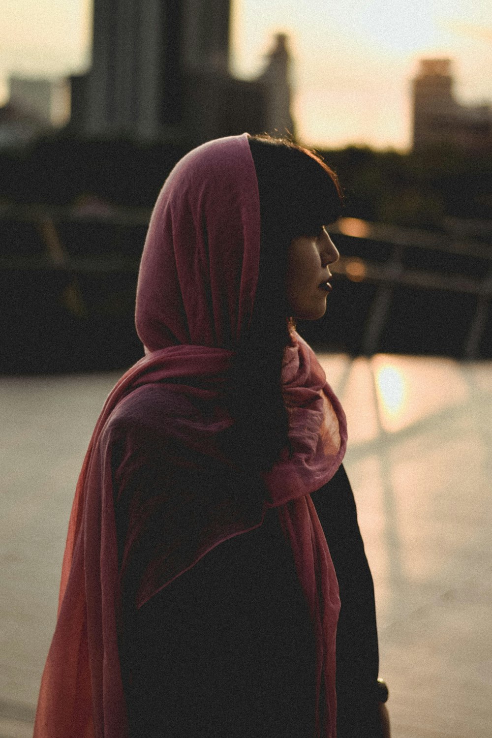 a woman wearing a pink scarf standing on a sidewalk