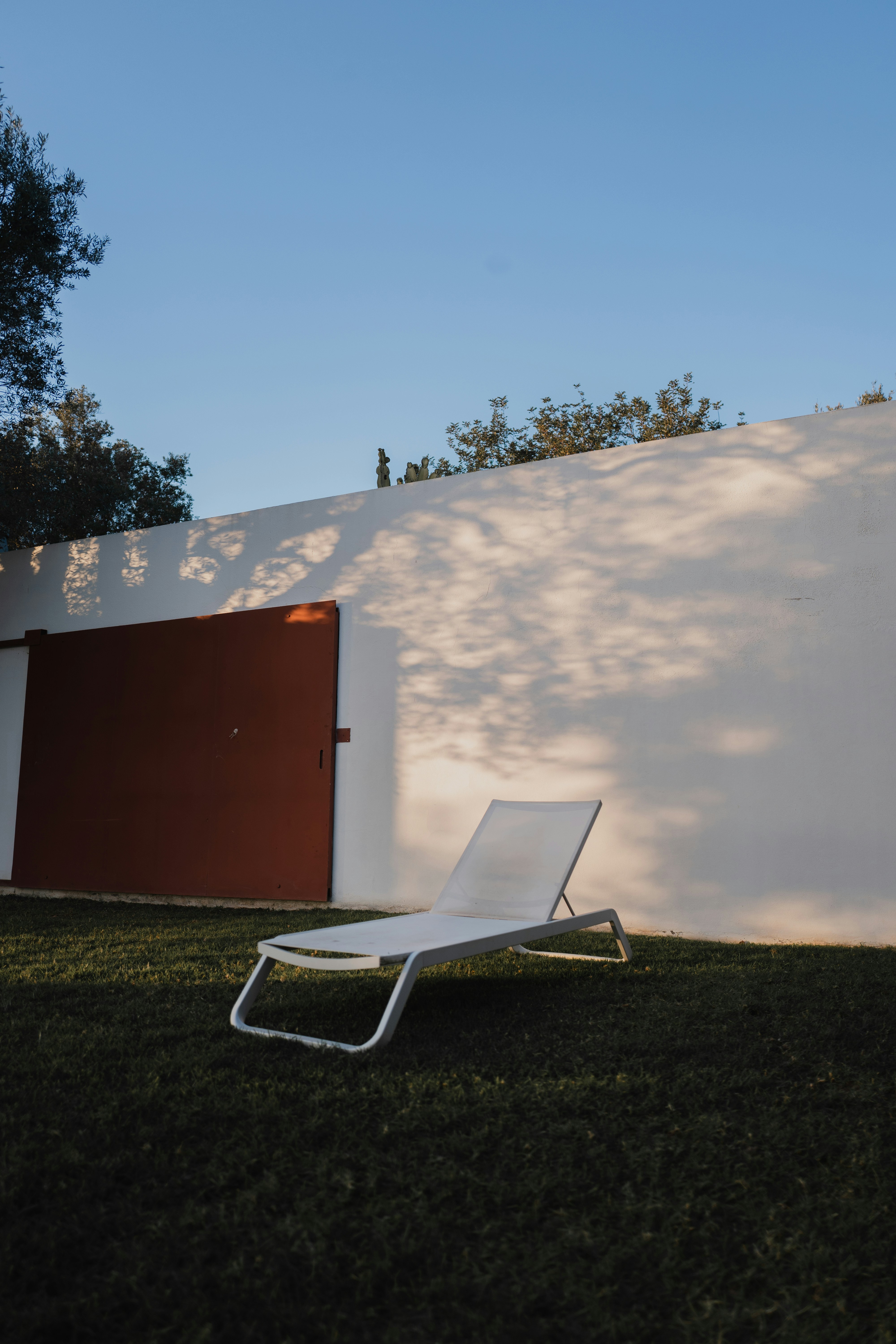 白い壁の前に座っている白い芝生の椅子