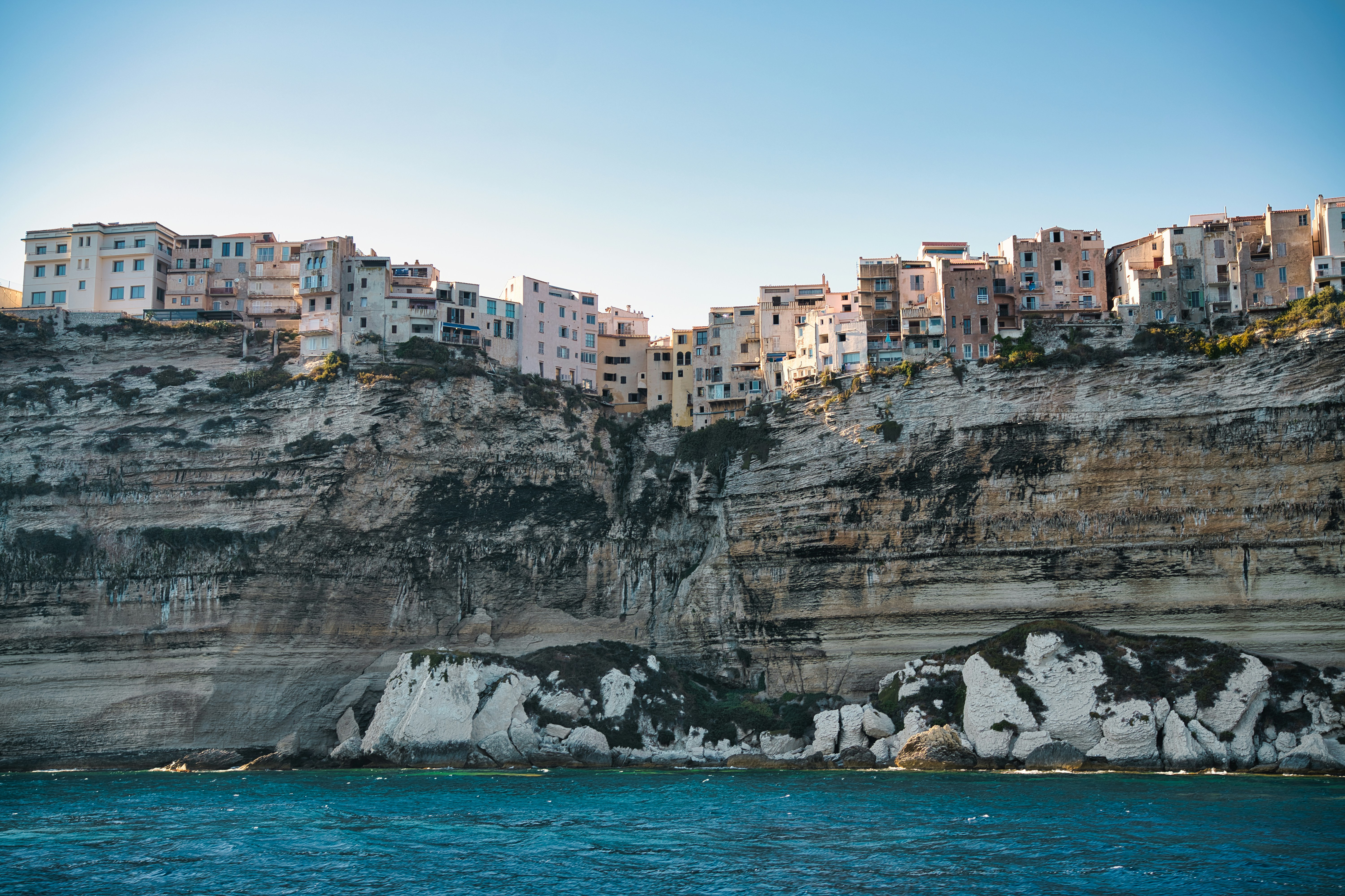 a city on the side of a cliff next to a body of water