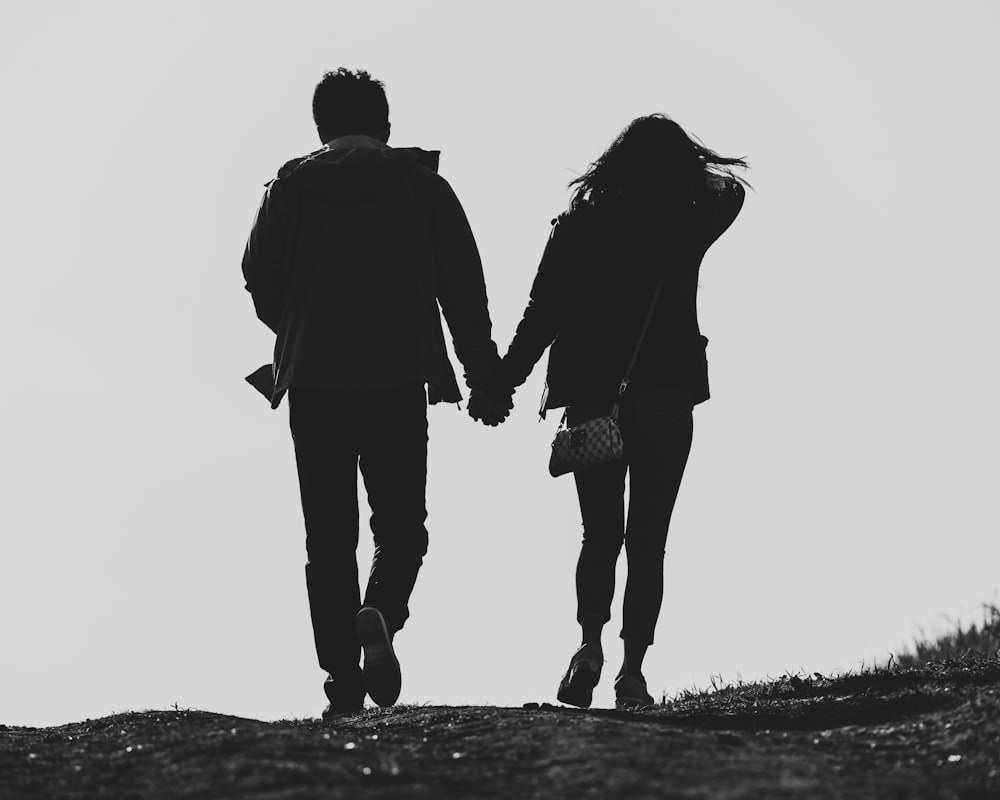 um homem e uma mulher descendo uma colina de mãos dadas