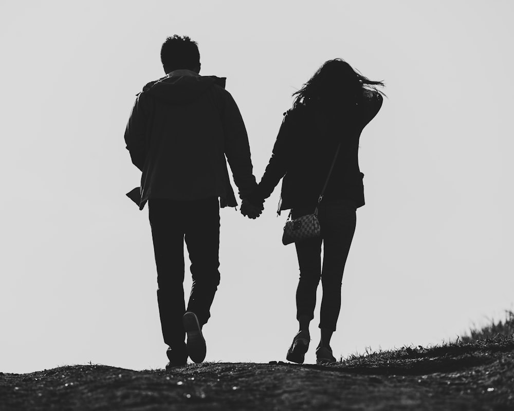 a man and a woman walking down a hill holding hands