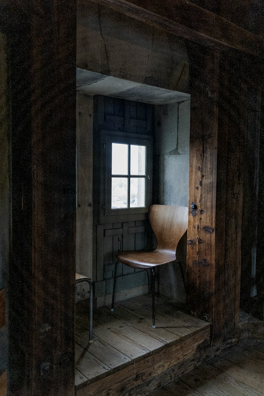 Una silla sentada en una habitación junto a una ventana