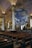 Inside a large, ornate church with high arched ceilings, there's an art installation featuring a giant globe suspended in the middle, surrounded by chandeliers. The church interior includes rows of wooden pews, large supporting columns, and intricate wrought iron details near the altar area. Stained glass windows allow natural light to filter through.