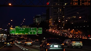 A busy highway lined with multiple digital billboards glowing brightly against the evening sky.
