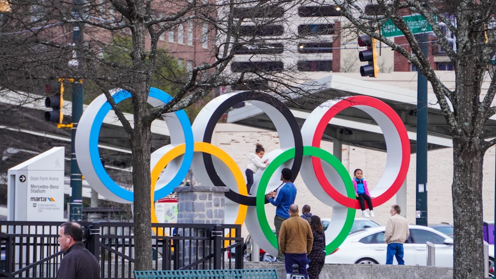 a group of people walking down a sidewalk next to a park