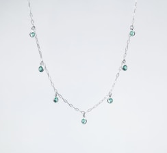 a silver necklace with green beads on a white background