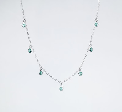 a silver necklace with green beads on a white background