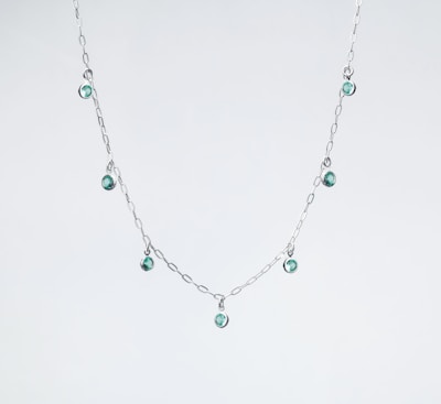 a silver necklace with green beads on a white background