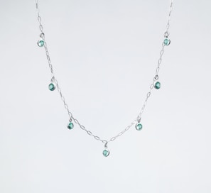 Close-up of a delicate pistachio green jade pendant on a simple silver chain.