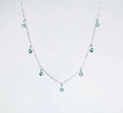 a silver necklace with green beads on a white background