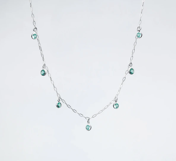 a silver necklace with green beads on a white background