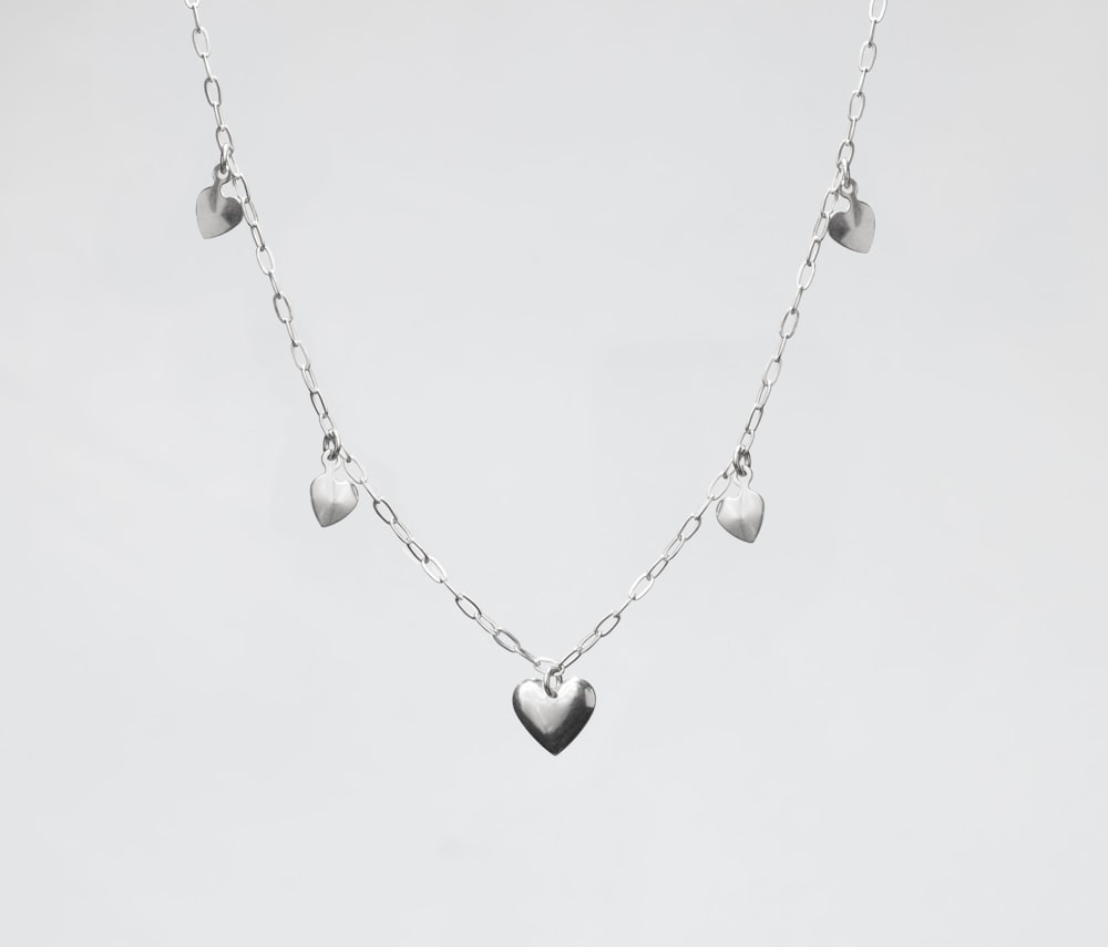 a silver heart necklace on a white background