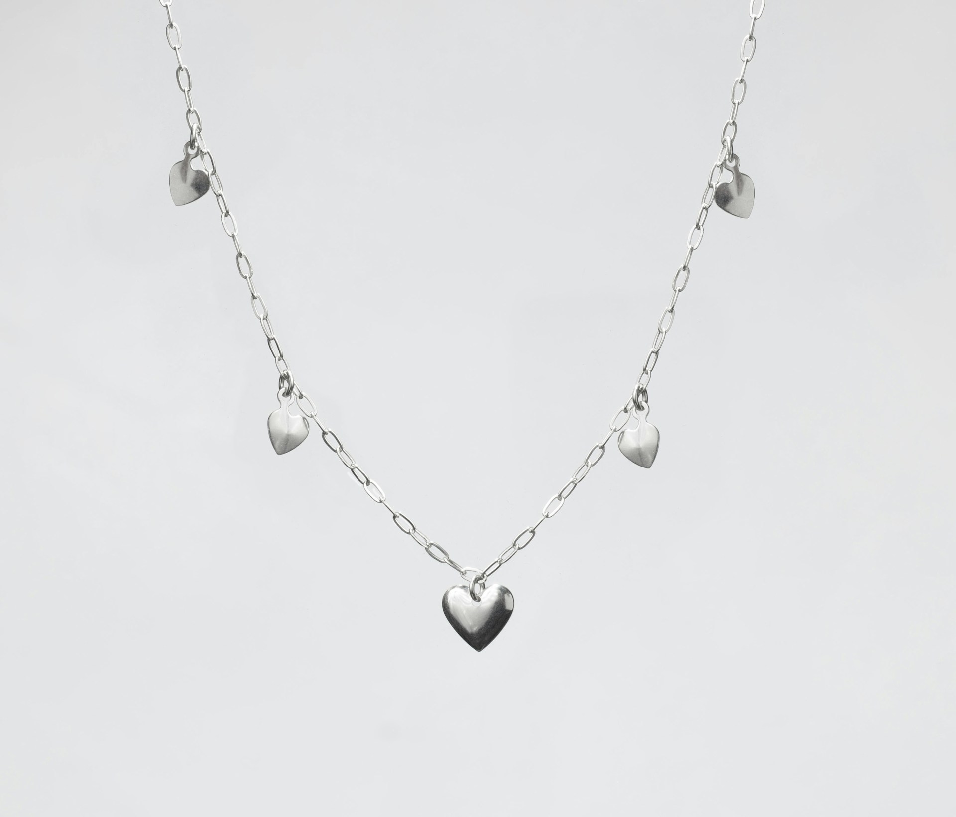 a silver heart necklace on a white background