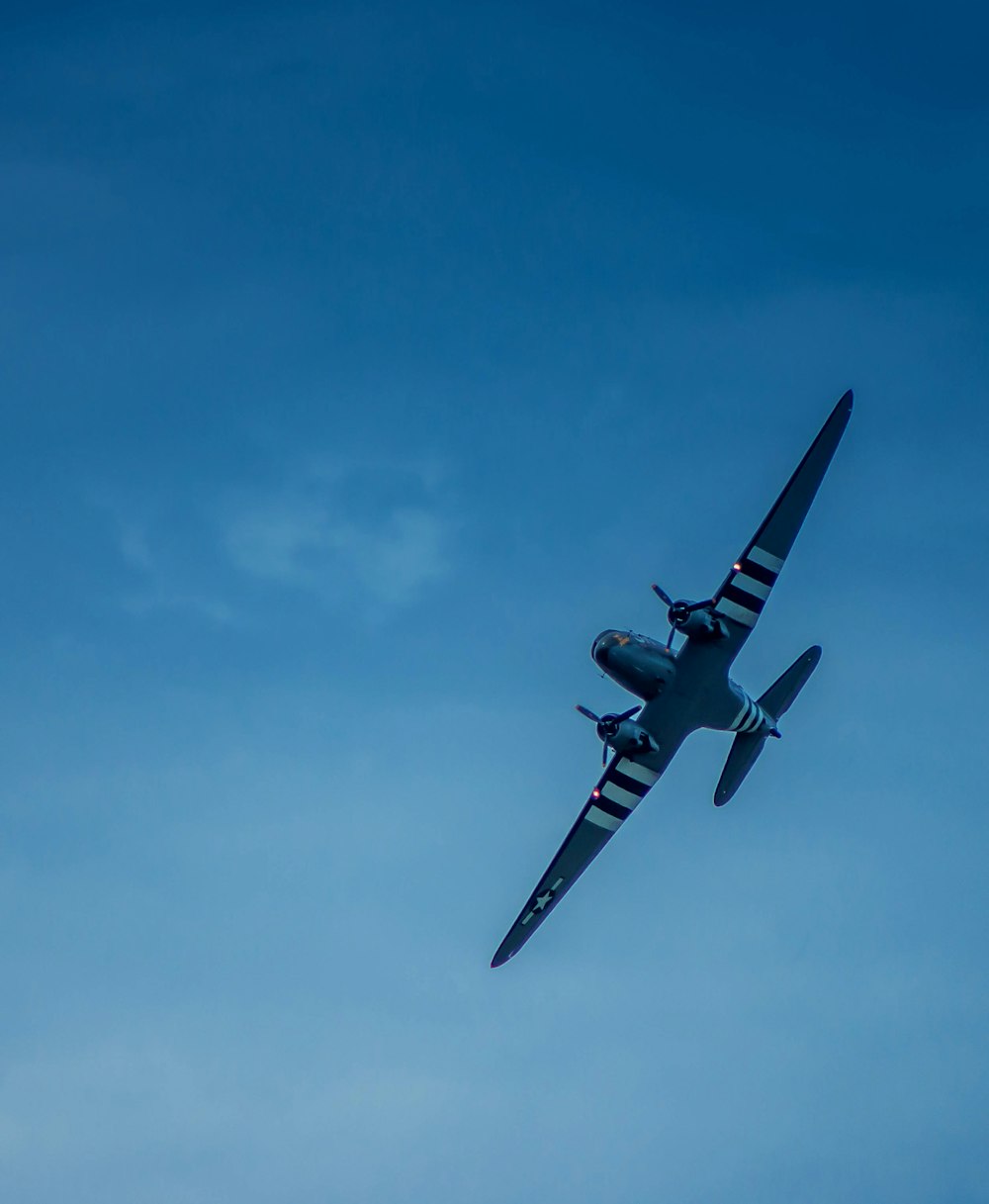 a small airplane flying through a blue sky