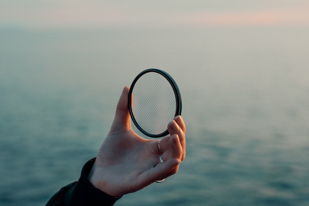 a person holding a tennis racquet over a body of water