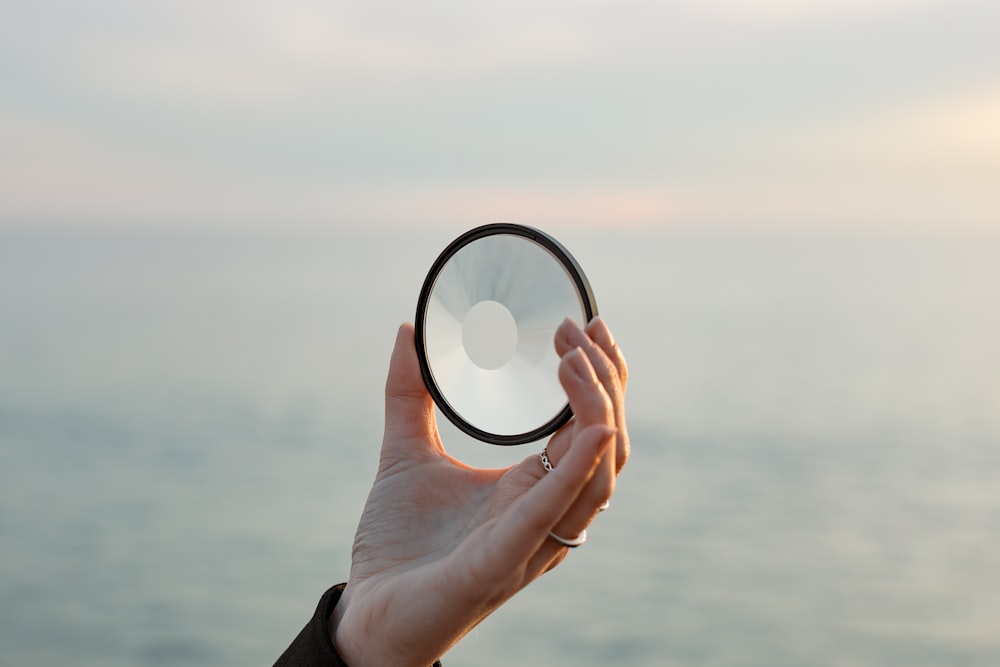 a person holding a magnifying glass in front of a body of water