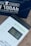 A Newpowa MPPT 100 solar charge controller is placed near a 100Ah lithium battery. The controller's display shows readings of 13.2 volts, 0.0 amps, and 77%. The battery, marked as LiFePO4, is dark blue with white text highlighting its specifications.