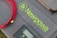 A grey textured surface features a coiled red cable, a grey device with digital display controls, and a soft case with the text 'Newpowa BE WISE GO SOLAR' in bright green lettering.