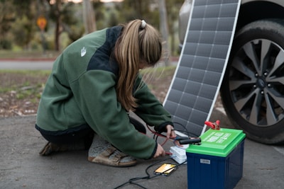 Technician connecting wiring for solar panel system on a sunny day.