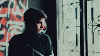 A smiling teenager wearing a donated beanie and scarf, standing in front of a frosted window.