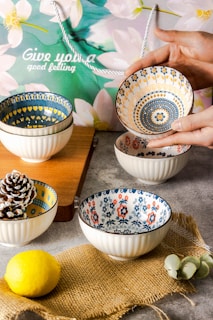 Close-up of hands arranging a beautifully patterned bowl from tabletrove on a rustic wooden table.