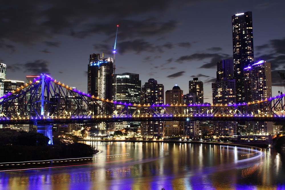 a city at night with a bridge and buildings lit up