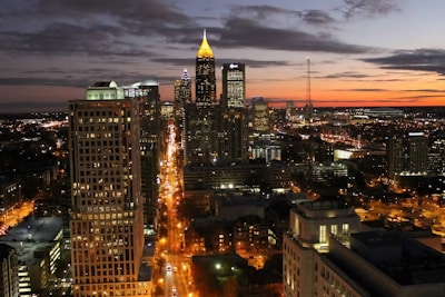 A vibrant cityscape at dusk with glowing streetlights and bustling streets.