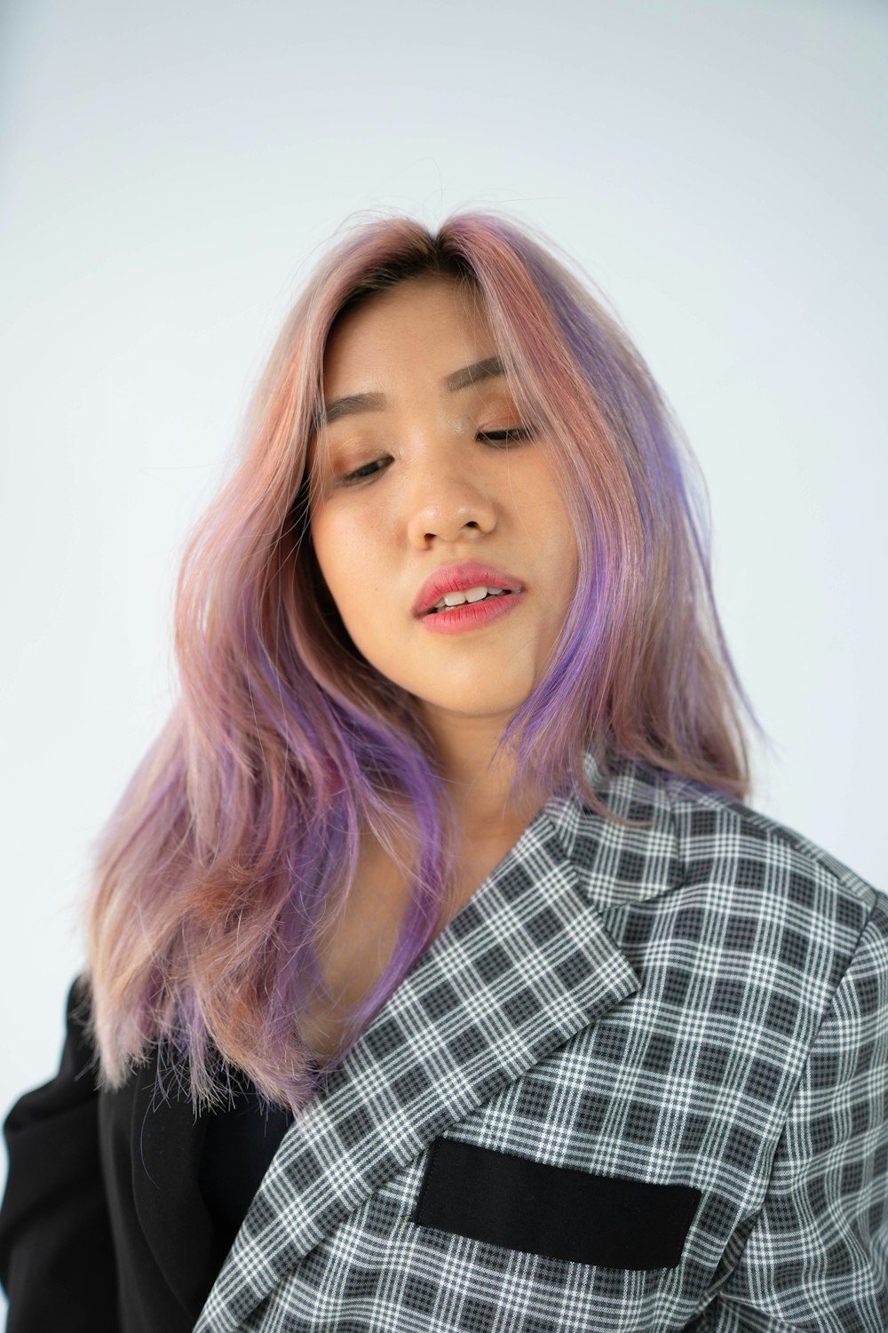 a woman with pink hair wearing a black and white checkered shirt