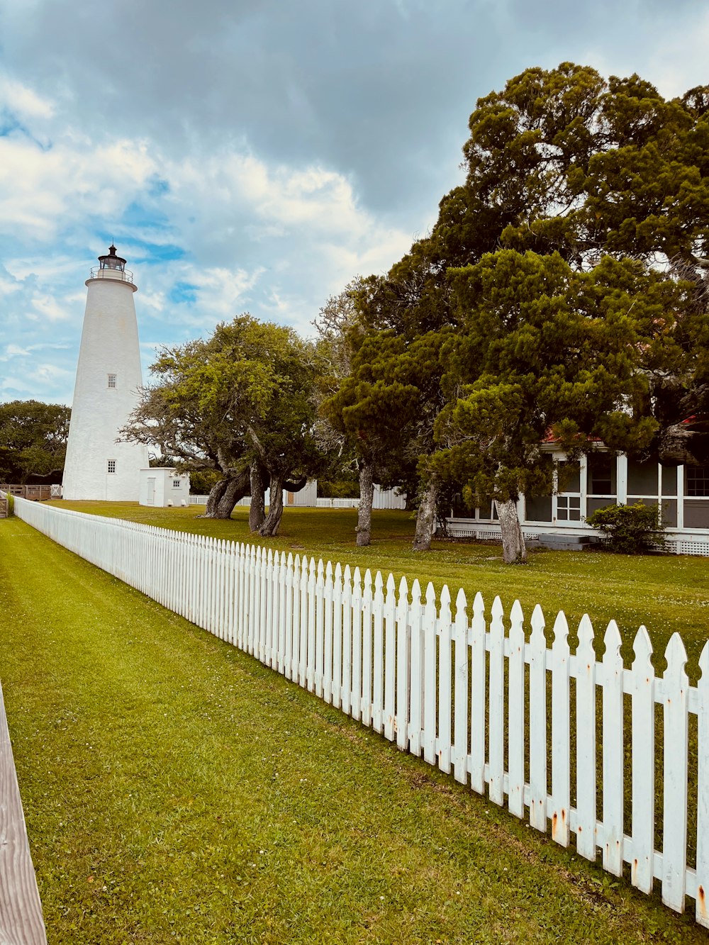 a white picket fence with a lighthouse in the background