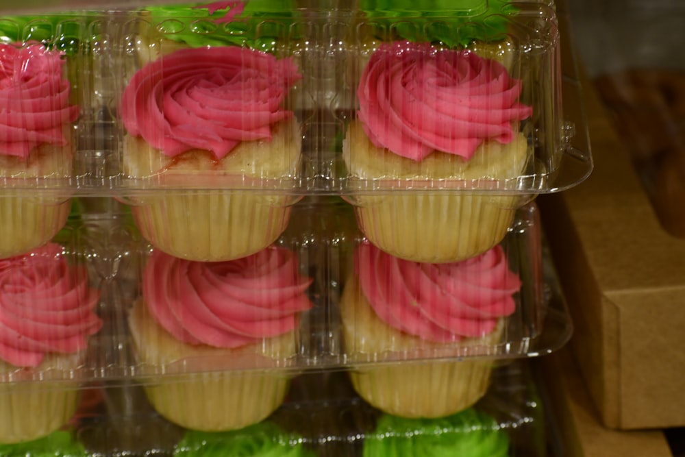 cupcakes with pink and green frosting in a plastic container