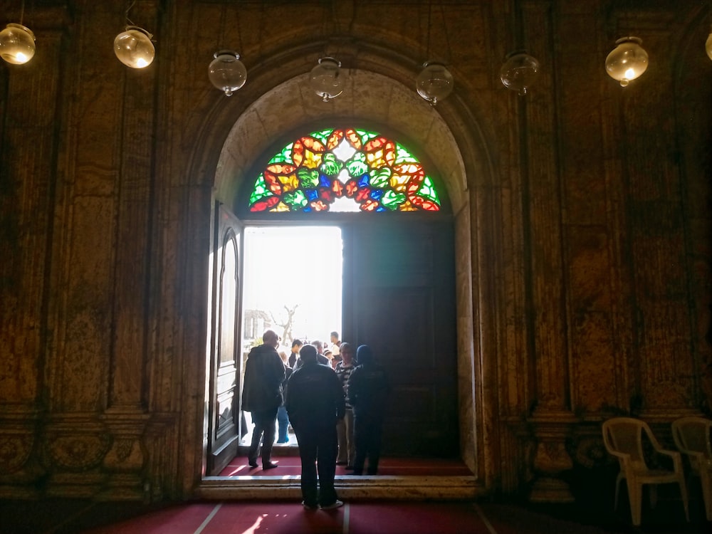 a group of people standing in front of a stained glass window