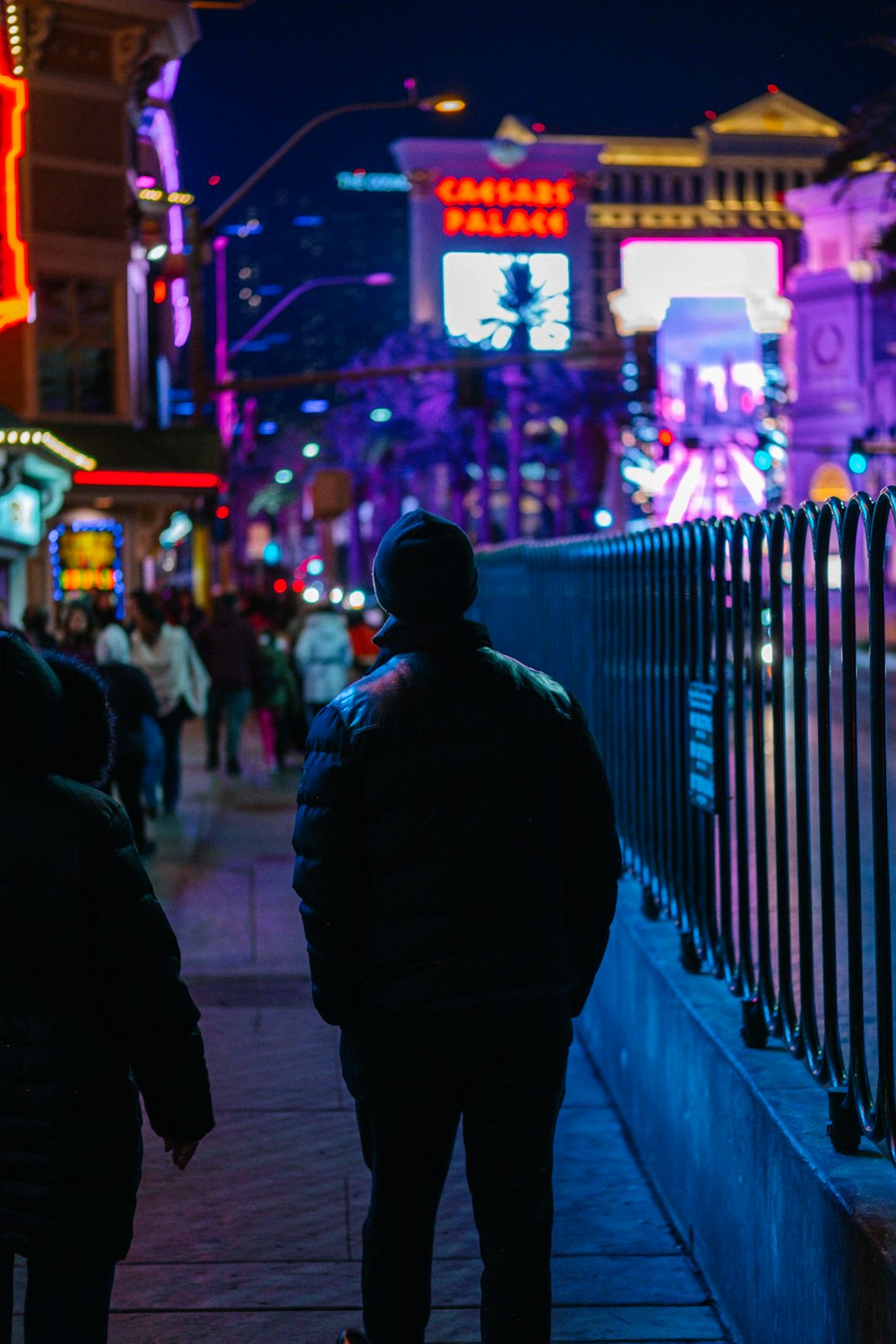 two people walking down a sidewalk at night