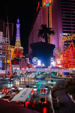 A busy downtown Las Vegas street at night with traffic moving past lit storefronts and hotels