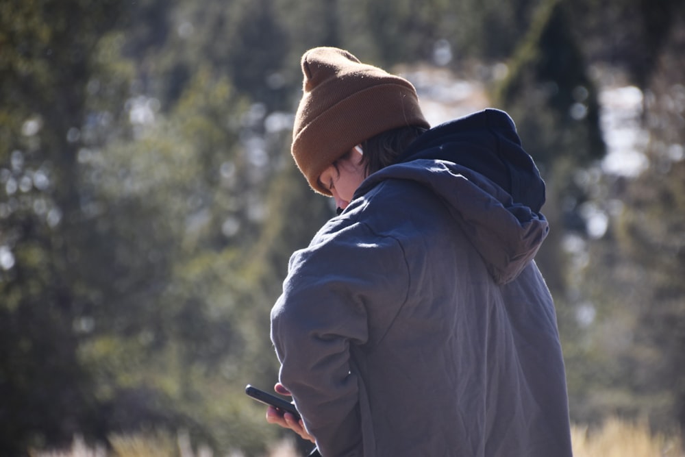 a person standing in a field looking at a cell phone