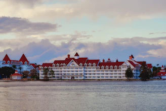 a large building with a red roof next to a body of water