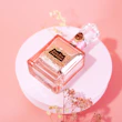 A delicate perfume bottle with soft pink pastel highlights on a white marble surface.