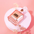 A delicate perfume bottle with soft pink pastel highlights on a white marble surface.