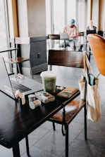 A cozy café table with a laptop, travel maps, and coffee, capturing the planning side of our journeys.