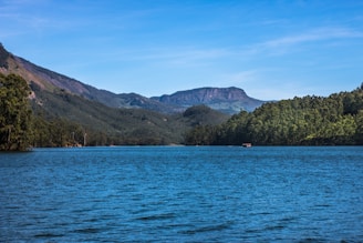 A serene lake surrounded by lush green hills and pine trees.