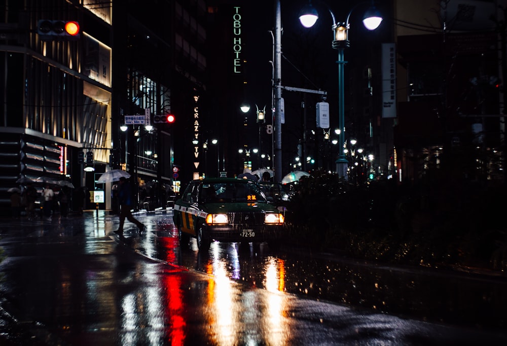 a city street at night with cars and people crossing the street