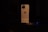 A smartphone with a gold-colored body is placed vertically on a dark surface. The back of the device is visible, featuring a distinctive logo and a multi-lens camera setup at the top left corner. The lighting is low, casting a soft glow on the phone and creating a dramatic contrast with the dark background.