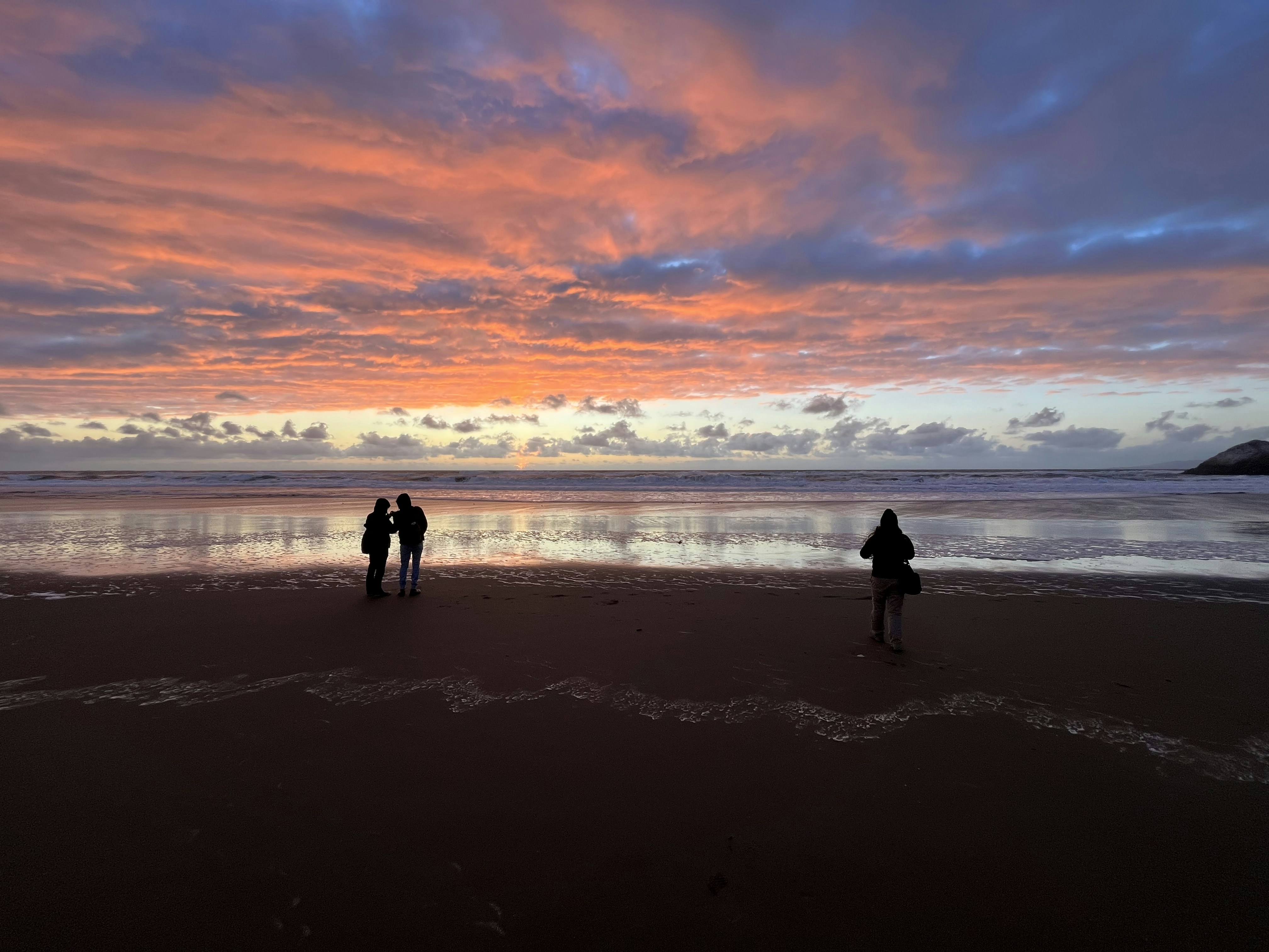 a couple of people standing on top of a beach