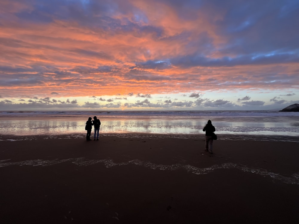 a couple of people standing on top of a beach