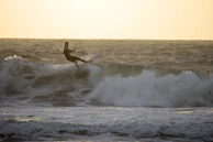A surfer riding a towering wave with sunlight sparkling on the water.
