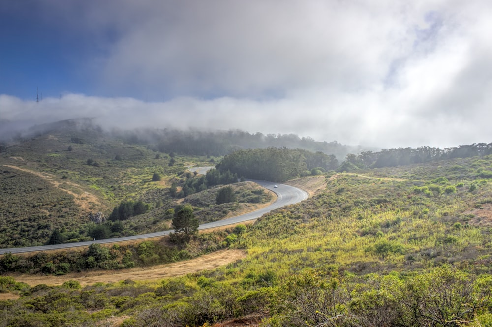 a winding road in the middle of a lush green hillside