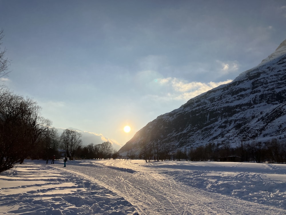 the sun is setting over a snowy mountain